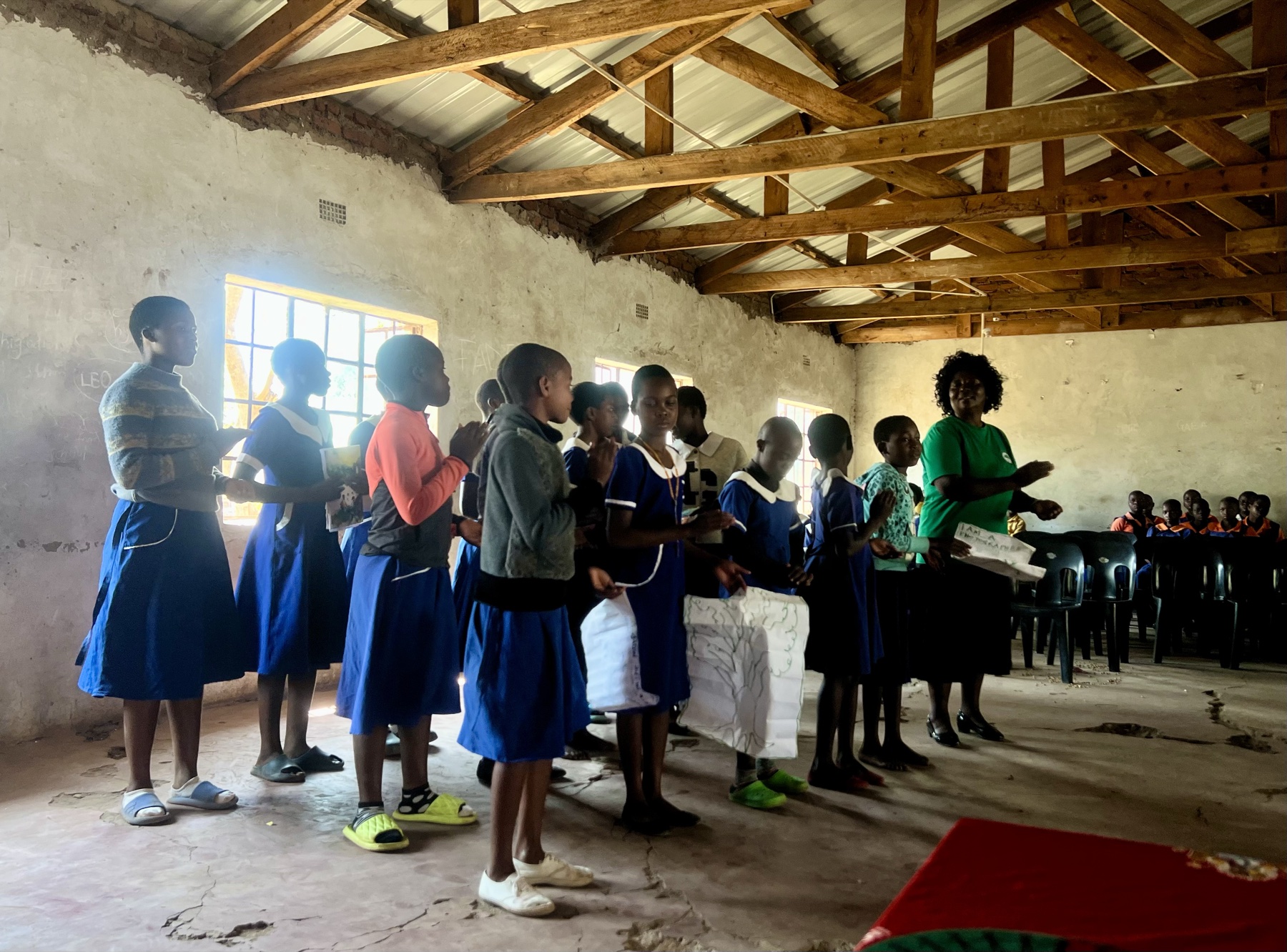Children lined up in a classroom holding the work they made, presenting to the room