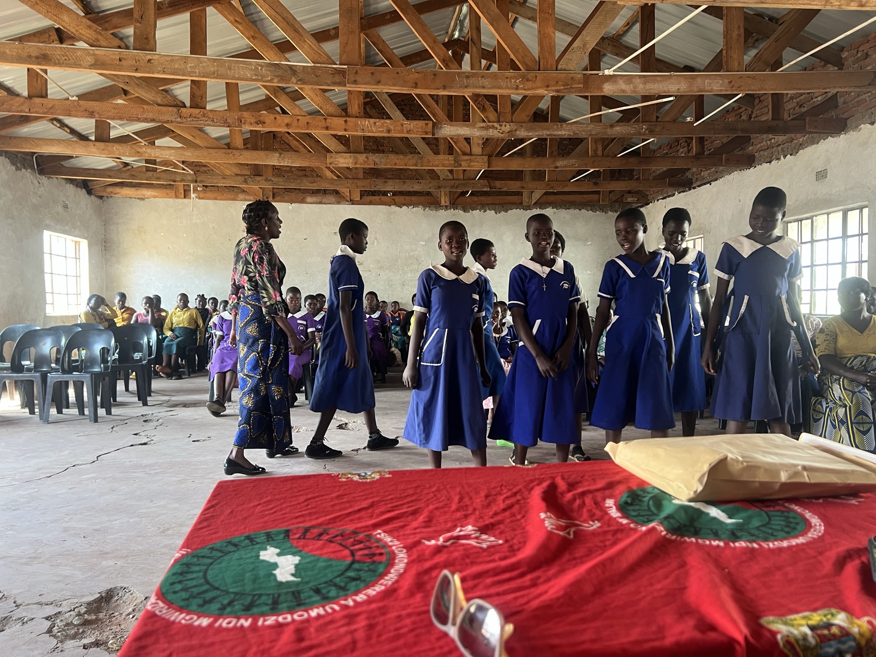 Girls in school uniform standing together at an I Am Who? graduation in a school hall